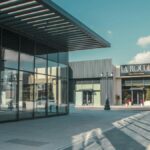 Elegant shopping arcade featuring modern architecture and glass facades under a clear sky.
