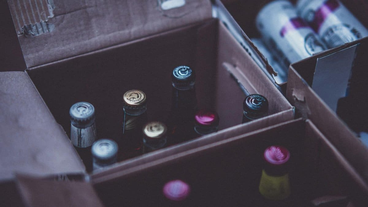 Close-up of various alcohol bottles and cans in cardboard boxes indoors.