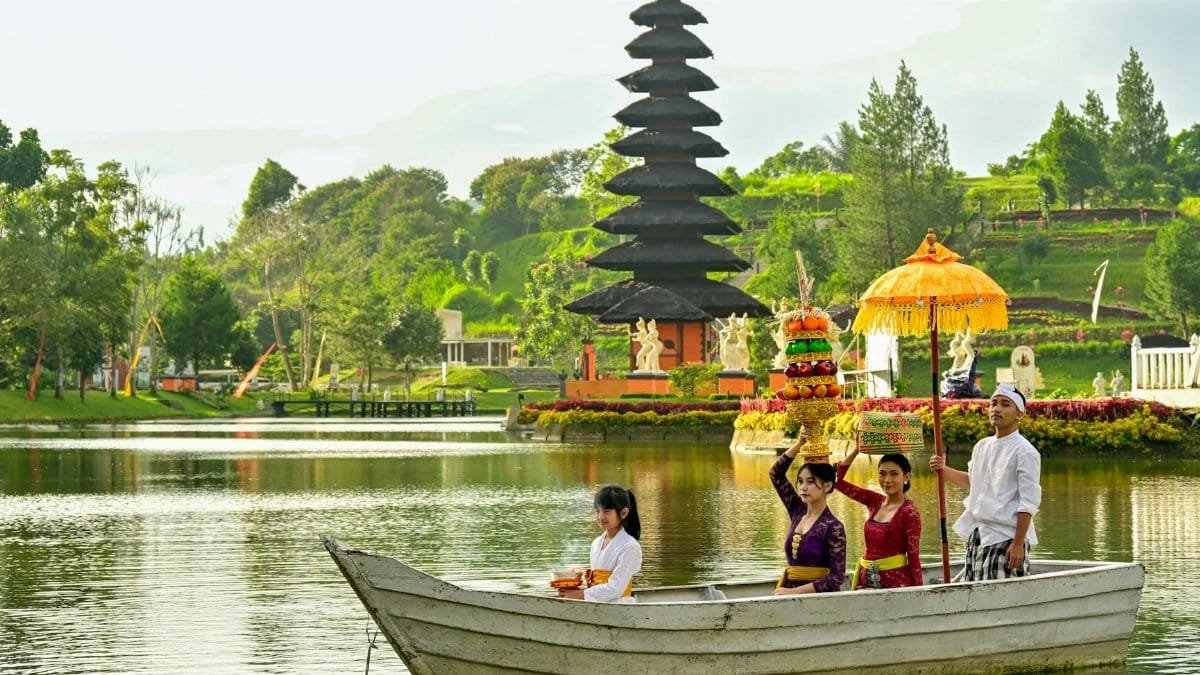 Traditional Balinese ceremony with locals on a boat near a temple in Indonesia.
