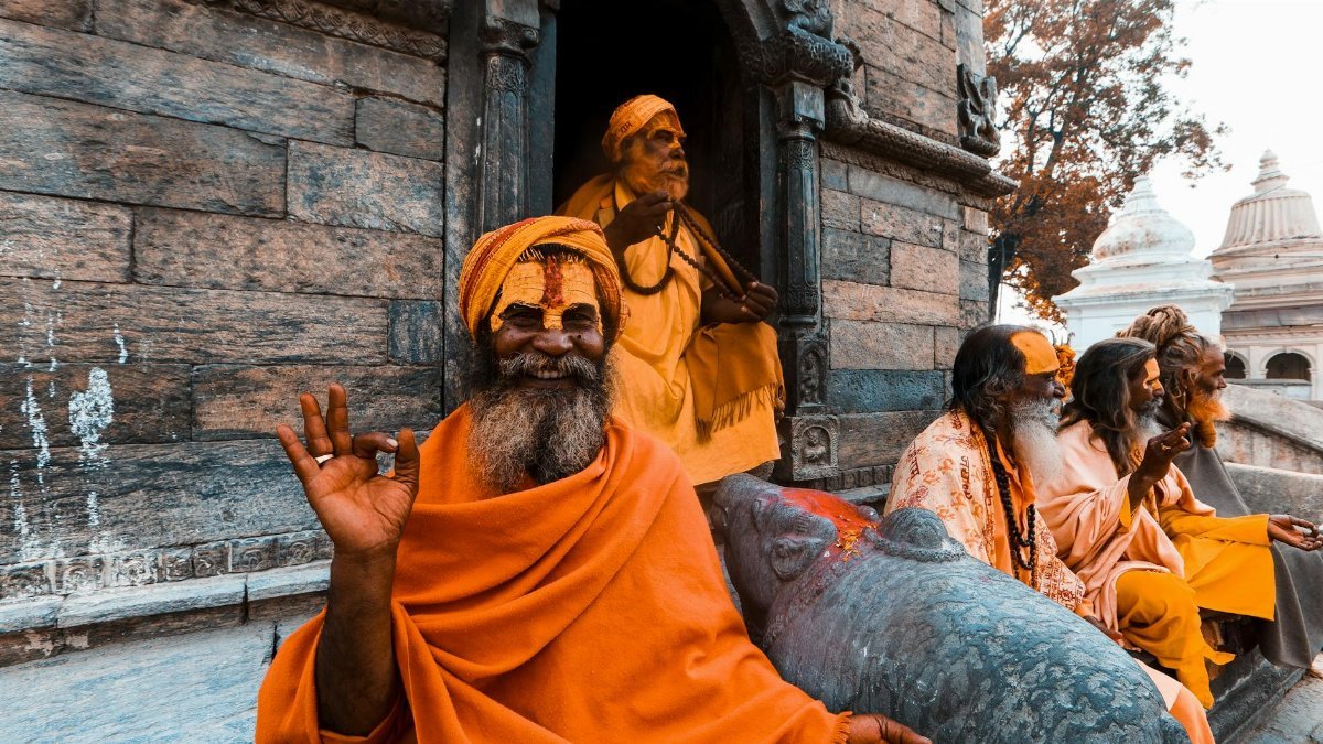 Monks in orange robes sitting at a historic temple, exuding spiritual tranquility.