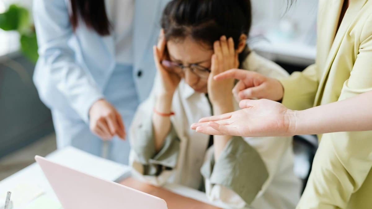 A stressed woman with colleagues in an office, showcasing teamwork and workplace dynamics.