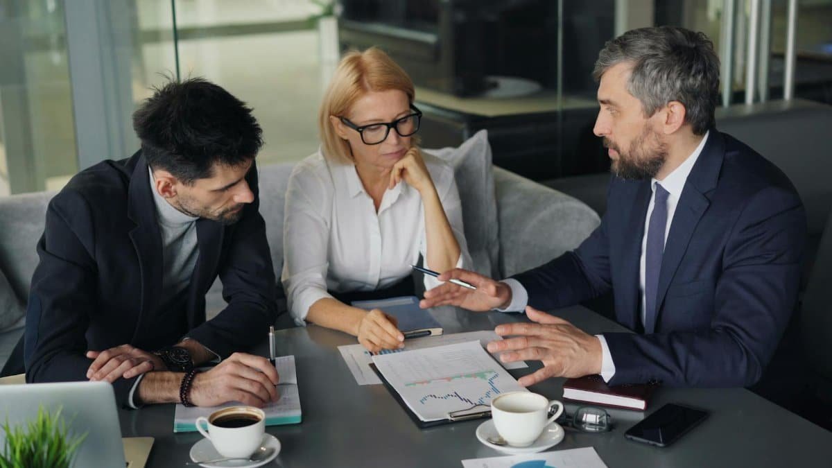 Professional colleagues engaged in a business meeting discussing strategy over coffee.
