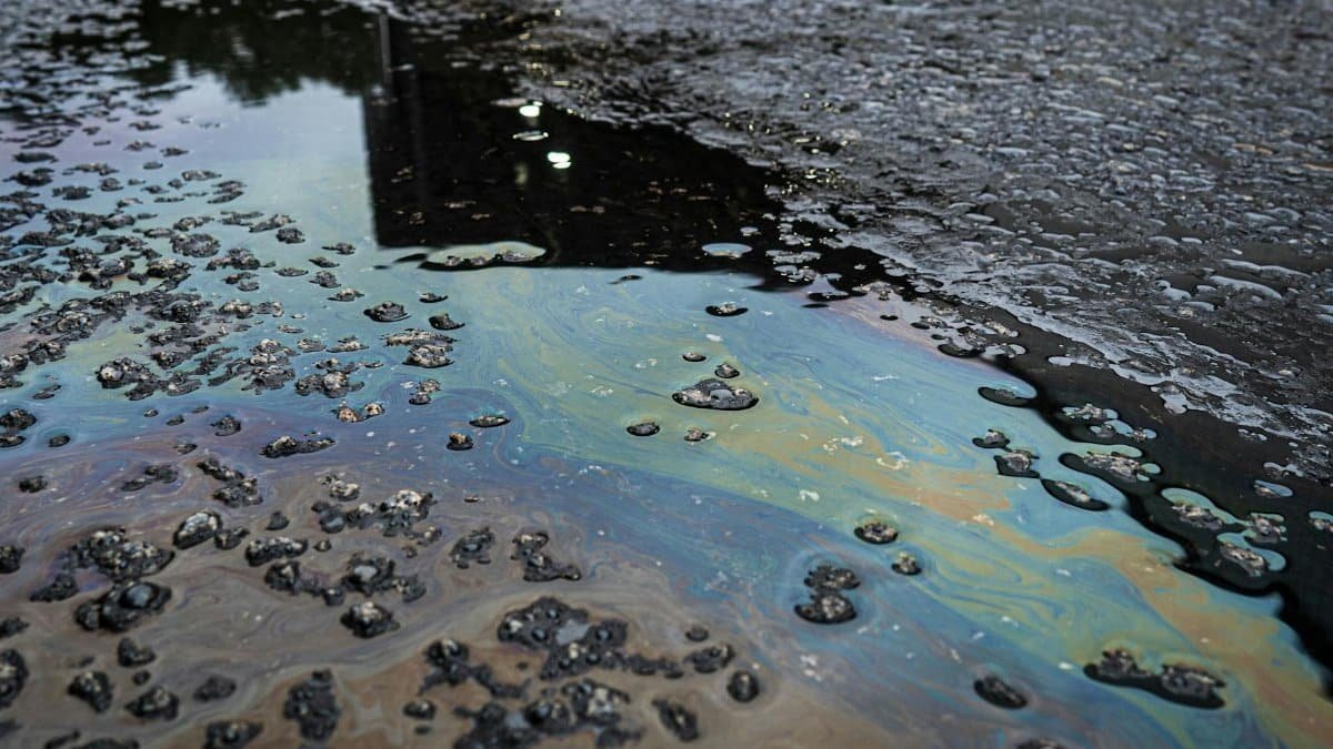 A vivid iridescent oil spill on rough asphalt surface, highlighting environmental contamination.