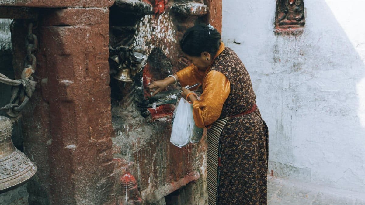 A woman engages in a traditional ritual at an ancient temple site.