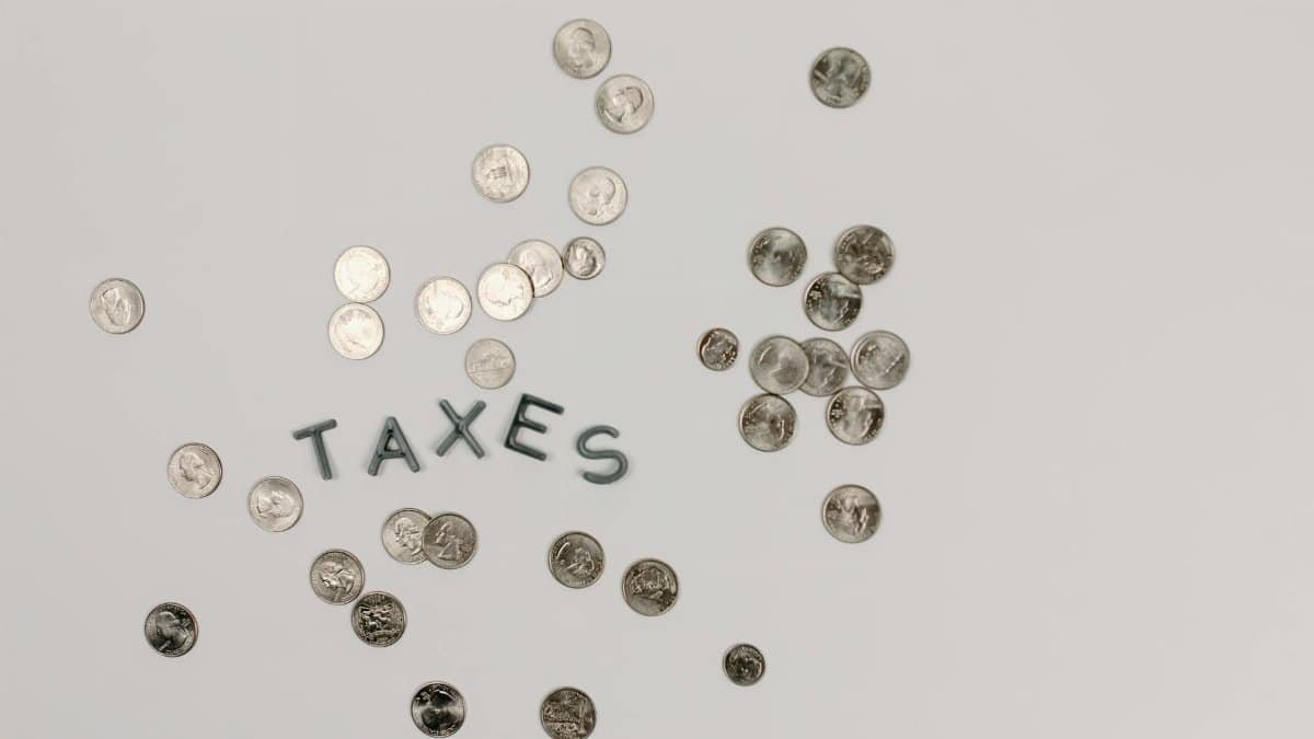 A visually striking flatlay of coins with 'Taxes' text on a white surface, ideal for financial concepts.