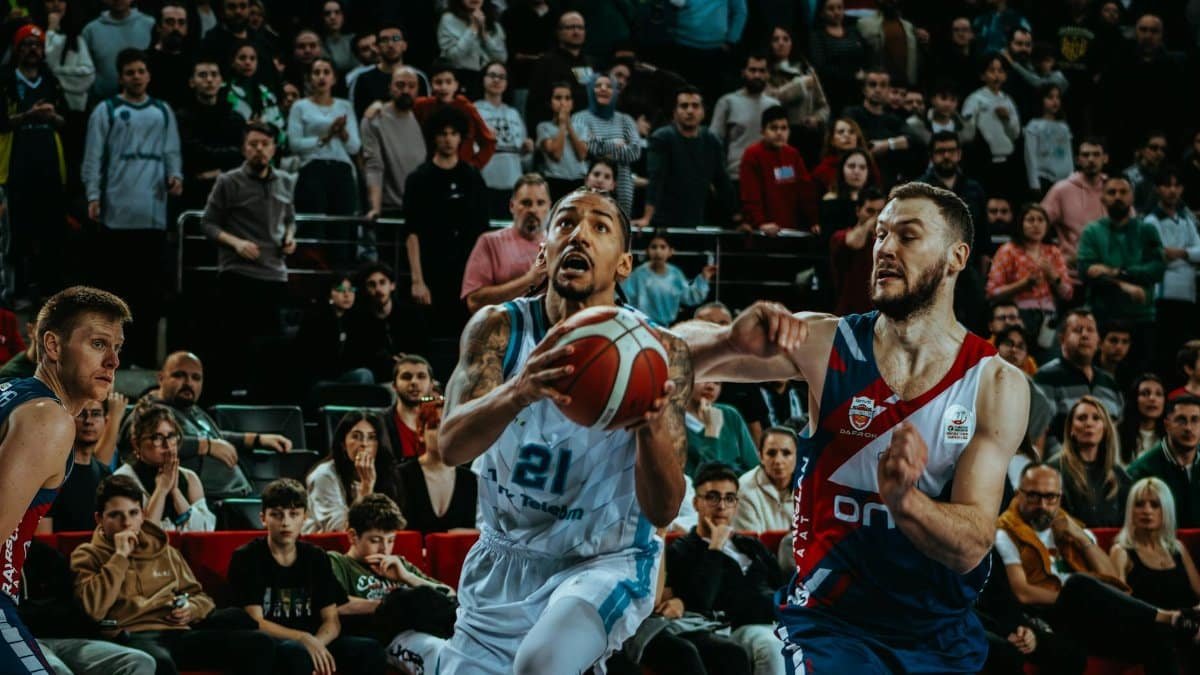 Dynamic action shot from a live basketball game capturing the competition and audience involvement.