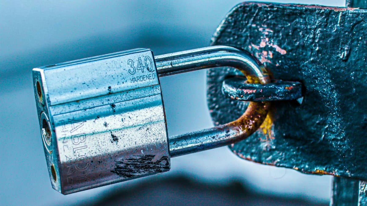 Detailed close-up of a durable padlock securing a rusted metal gate, emphasizing safety and protection.