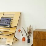 Minimalist standing desk setup with laptop, book, and decor in a home office.