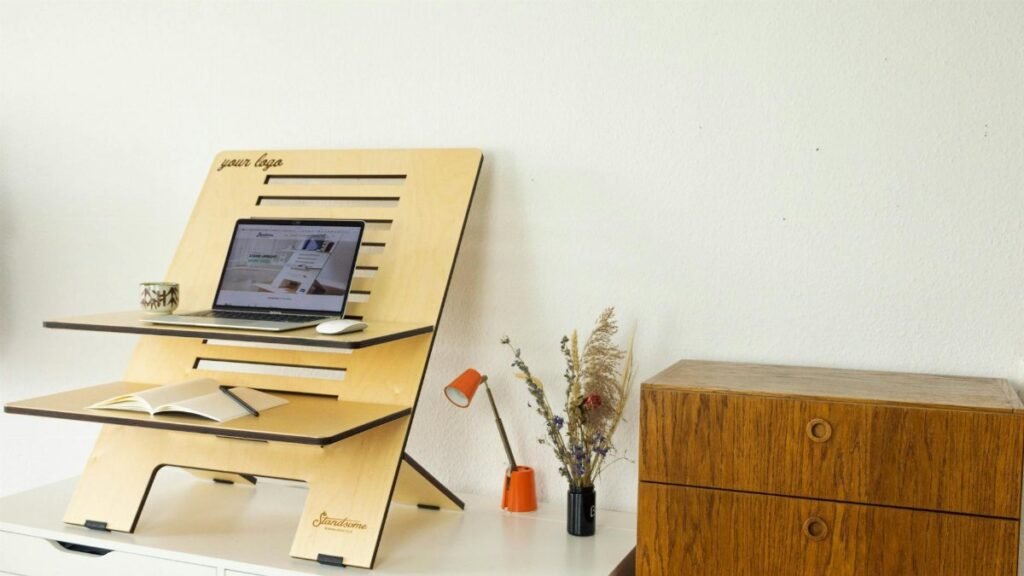 Minimalist standing desk setup with laptop, book, and decor in a home office.