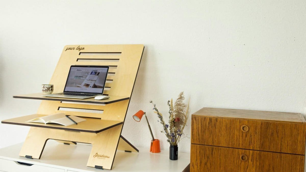 Minimalist standing desk setup with laptop, book, and decor in a home office.