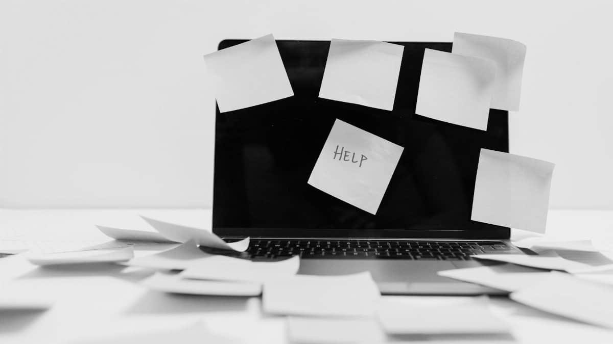 Monochrome image featuring sticky notes covering a laptop screen, symbolizing workplace chaos.