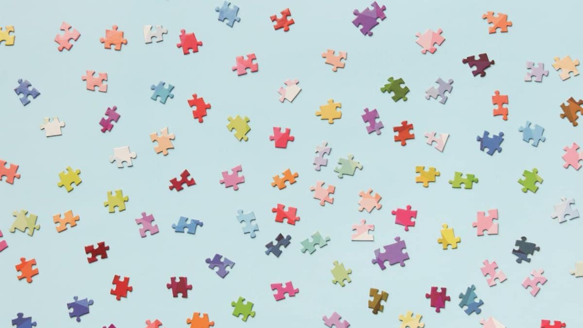 Scattered colorful puzzle pieces on a light blue background offer a vibrant and playful composition.