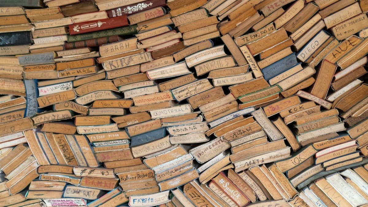 A large collection of vintage books with handwritten titles seen from above, offering a unique literary texture.