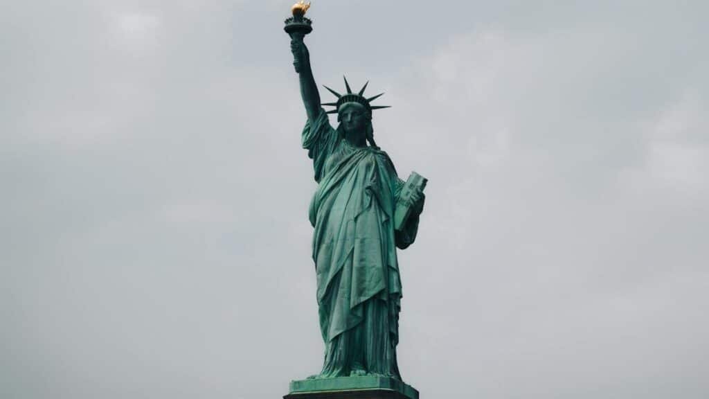 The Statue of Liberty stands tall against a cloudy sky in New York City, symbolizing freedom.