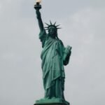 The Statue of Liberty stands tall against a cloudy sky in New York City, symbolizing freedom.