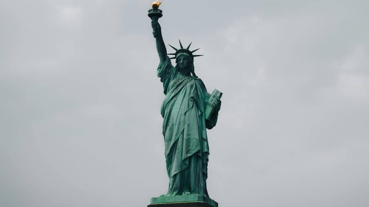 The Statue of Liberty stands tall against a cloudy sky in New York City, symbolizing freedom.