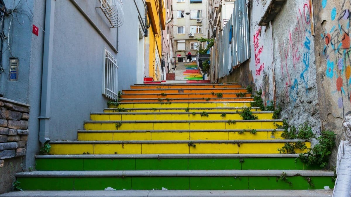 A vibrant urban staircase with colorful steps in a residential area, decorated with graffiti.