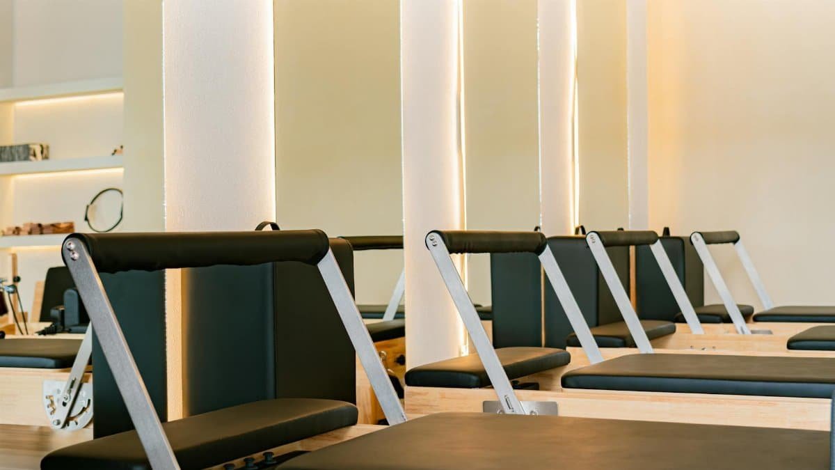 Interior of a modern Pilates studio featuring multiple reformer machines in a calming atmosphere.