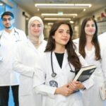 Group of diverse medical students wearing lab coats in university corridor, representing future healthcare professionals.