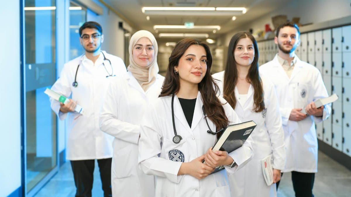 Group of diverse medical students wearing lab coats in university corridor, representing future healthcare professionals.