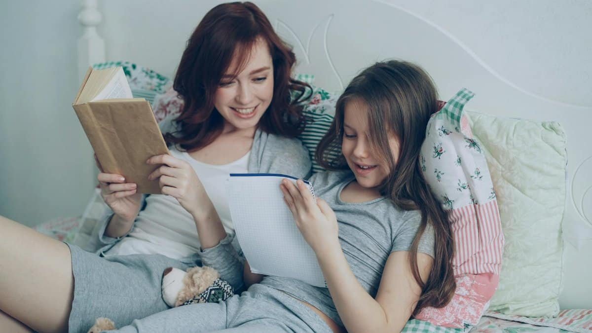A mother and daughter enjoy reading together in a cozy bedroom setting, bonding over books and laughter.