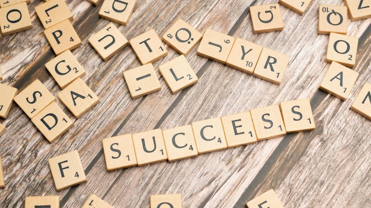 Close-up of wooden letter tiles spelling 'success' on rustic surface, symbolizing achievement and goals.