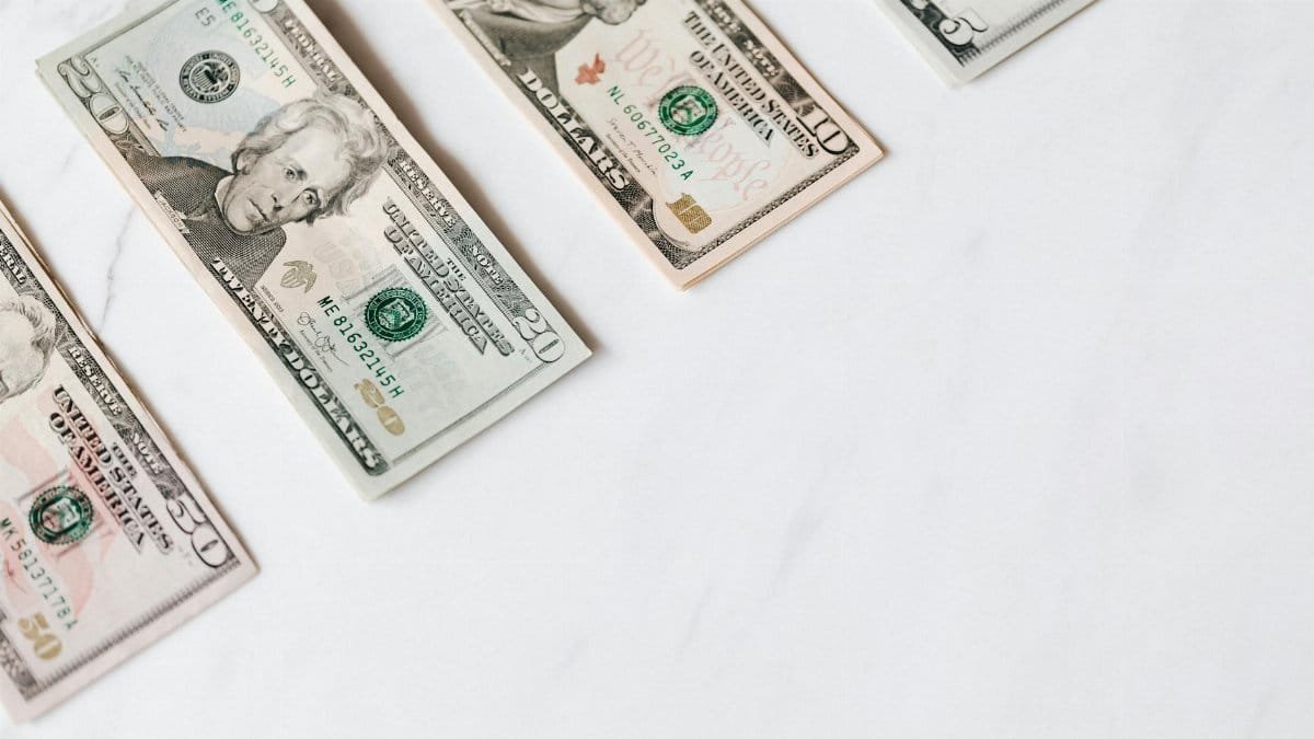 From above of US dollar banknotes in different denominations placed in row on white surface