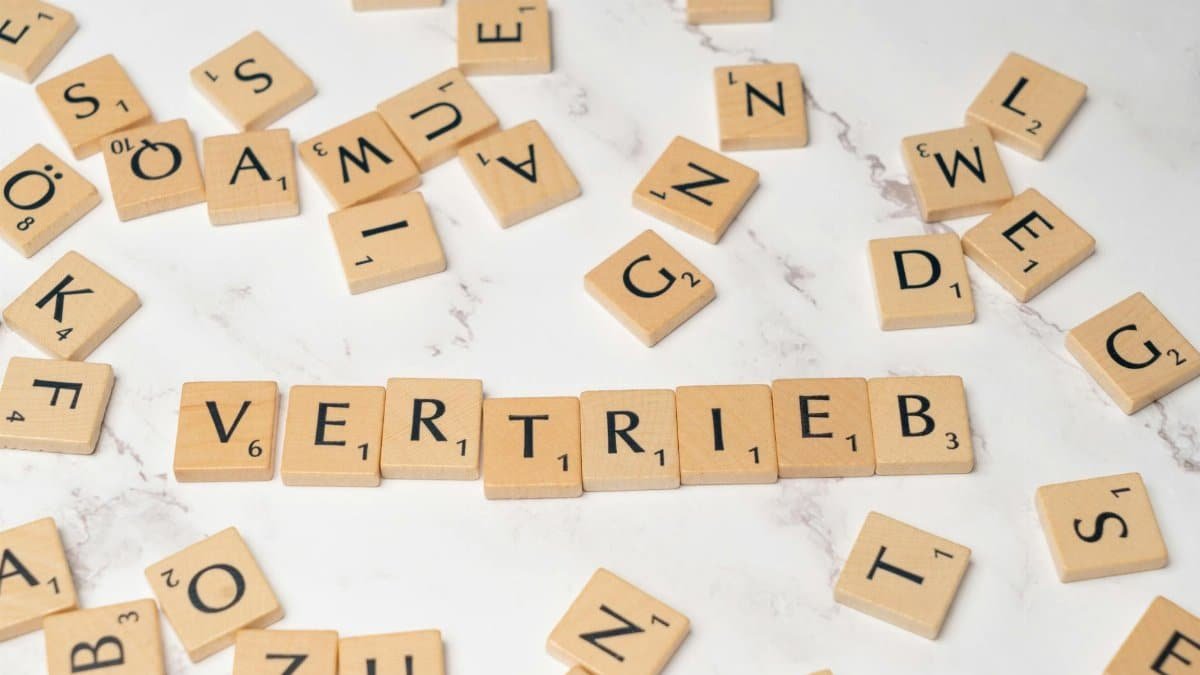 Scrabble tiles arranged to spell 'Vertrieb' on a marble surface, symbolizing sales.