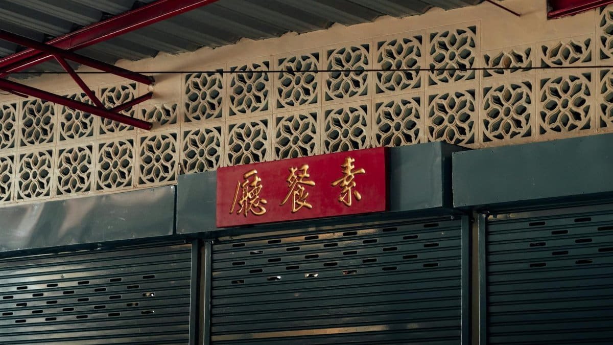 A closed storefront in Bangkok with traditional architectural details and Chinese characters on a sign.