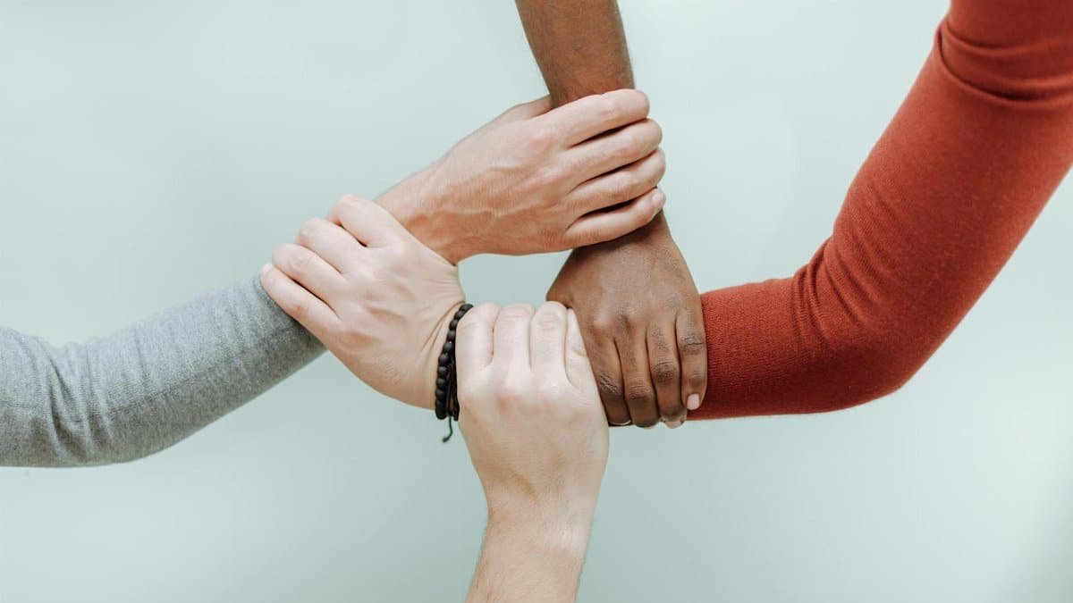 Close-up of diverse hands holding each other in a symbol of unity and togetherness.