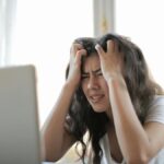 Frustrated woman struggling with remote work stress and digital challenges indoors.