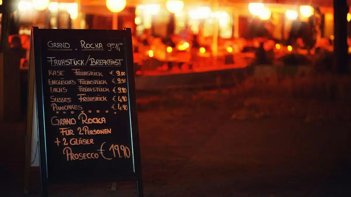 Chalkboard menu outside a Berlin restaurant, illuminated at night, offering breakfast options.