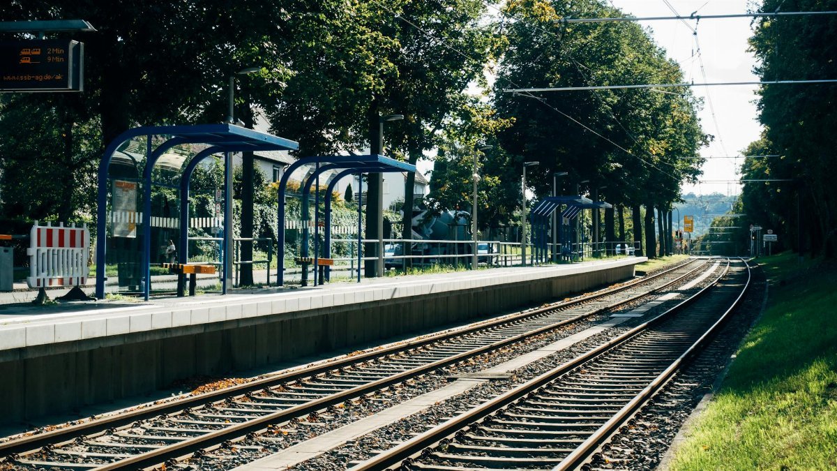 Scenic view of a train station platform and tracks in Stuttgart surrounded by greenery.