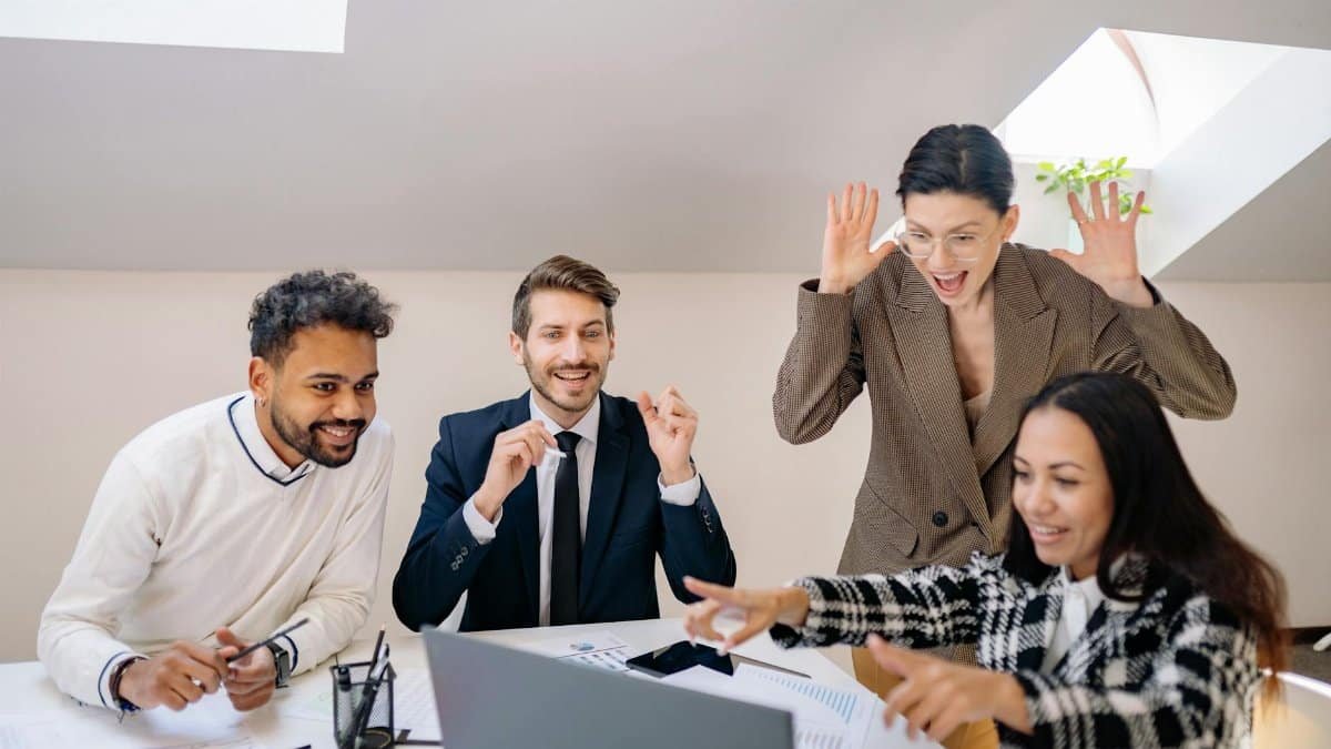 Happy diverse team of colleagues celebrating success in a modern office setting.