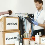 Volunteer organizing various goods for donation. Charitable cause and community support.