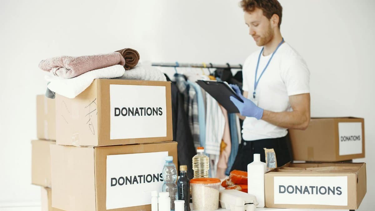 Volunteer organizing various goods for donation. Charitable cause and community support.