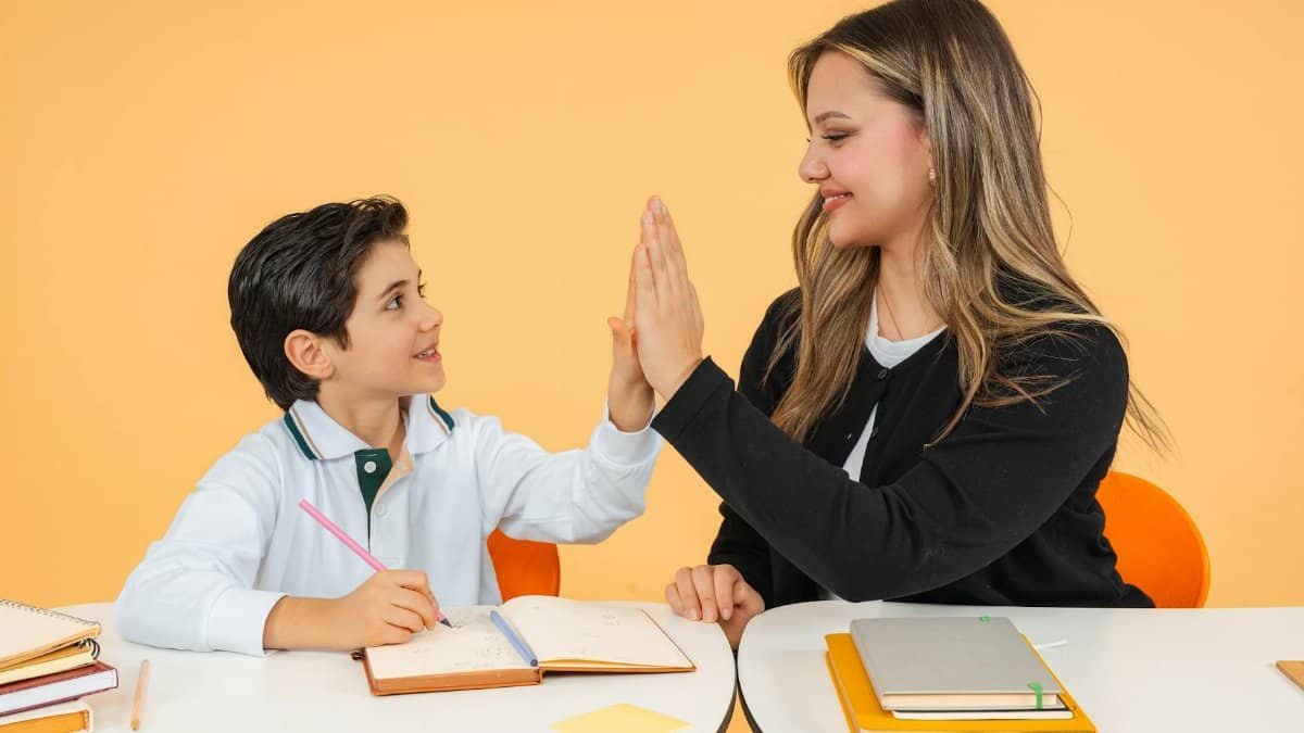 A teacher and student exchange a high-five in a classroom, fostering a positive learning environment.