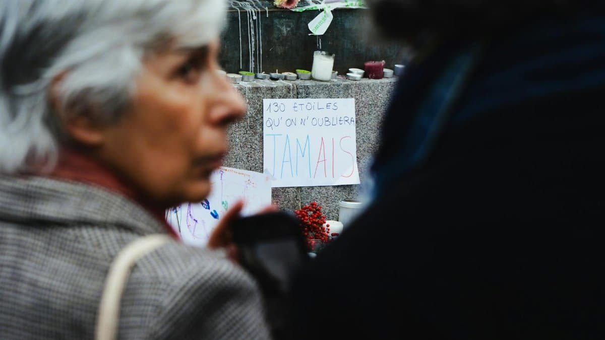 Emotional scene at a memorial vigil with text sign and candles.