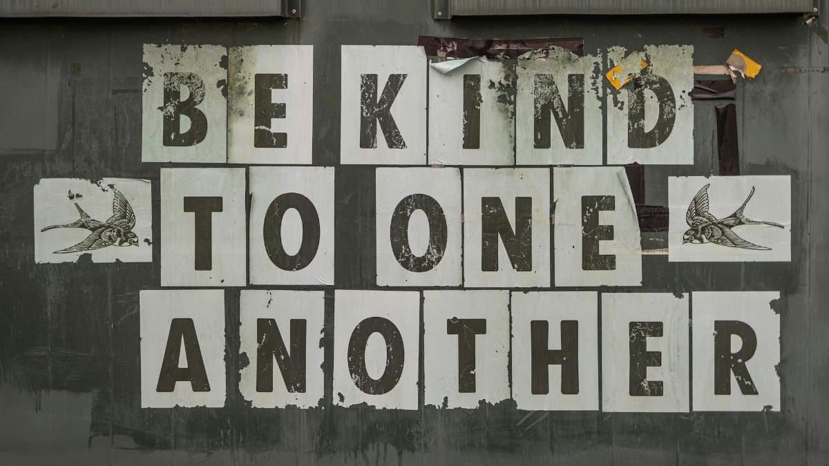 Close-up of 'Be Kind to One Another' message on a weathered background.