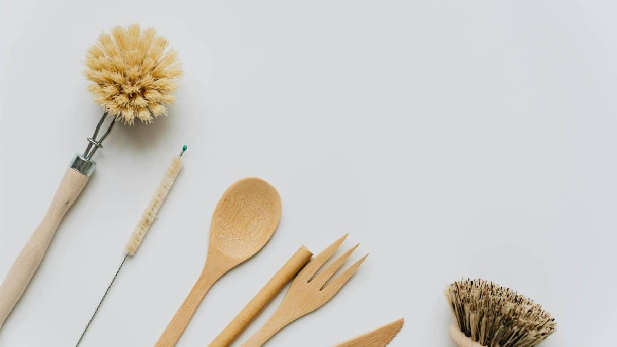 Flat lay of wooden kitchen utensils and brushes promoting eco-friendly lifestyle and sustainability.