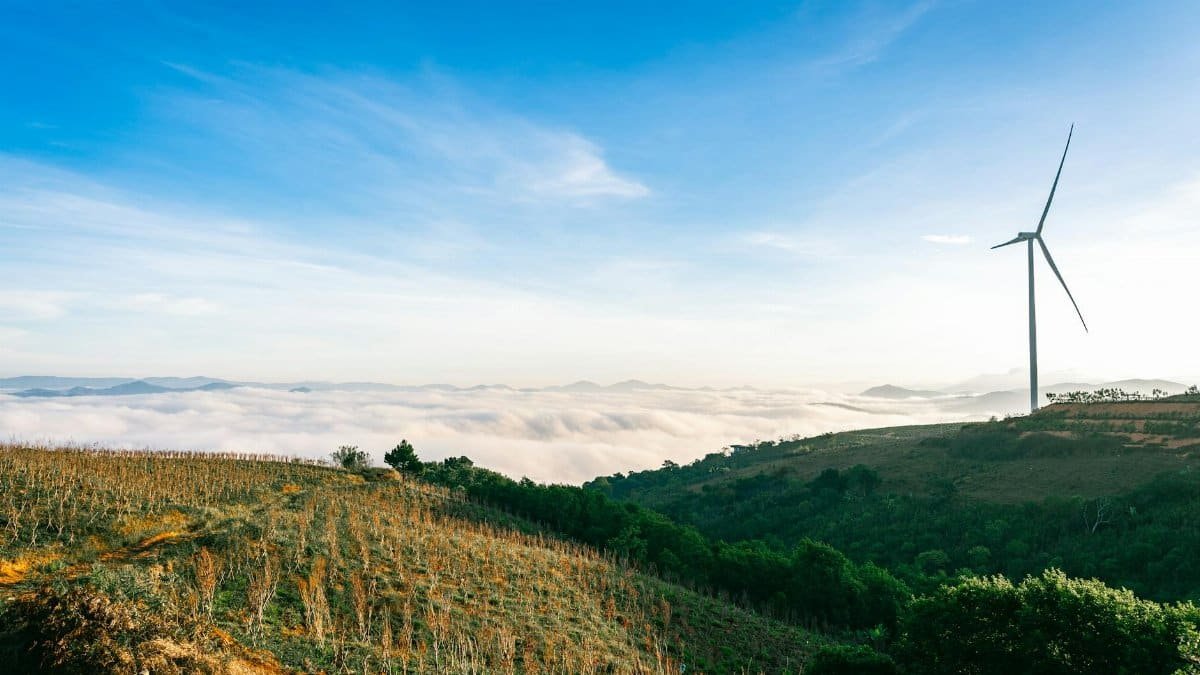 Wind turbine on a hilly landscape with clouds in Dalat, Vietnam, showcasing sustainable energy.