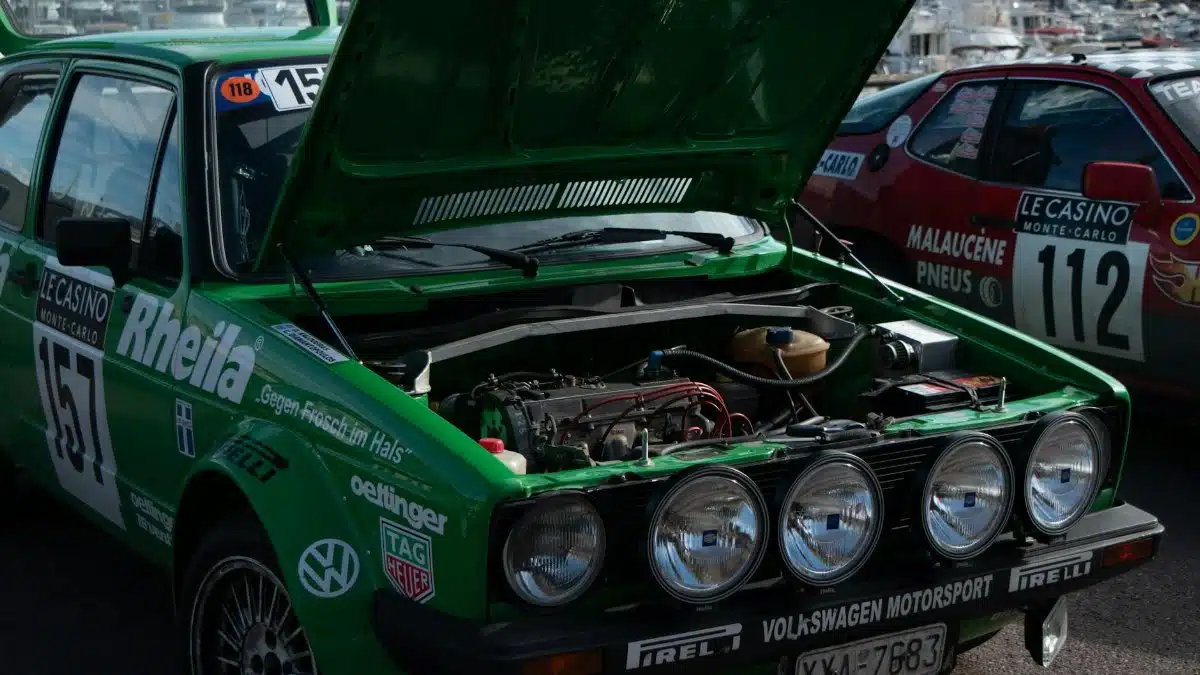 Green rally car with open hood, exposed engine at Monaco event.