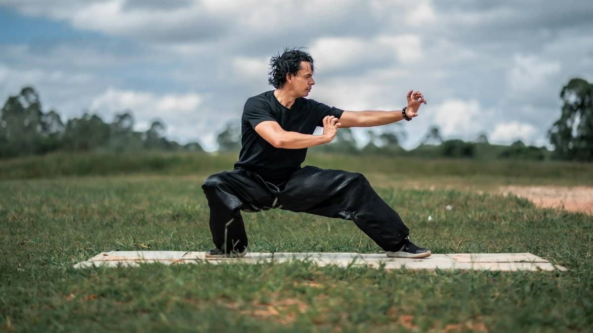 Man performing tai chi in a peaceful outdoor setting, focusing on balance and mindfulness.
