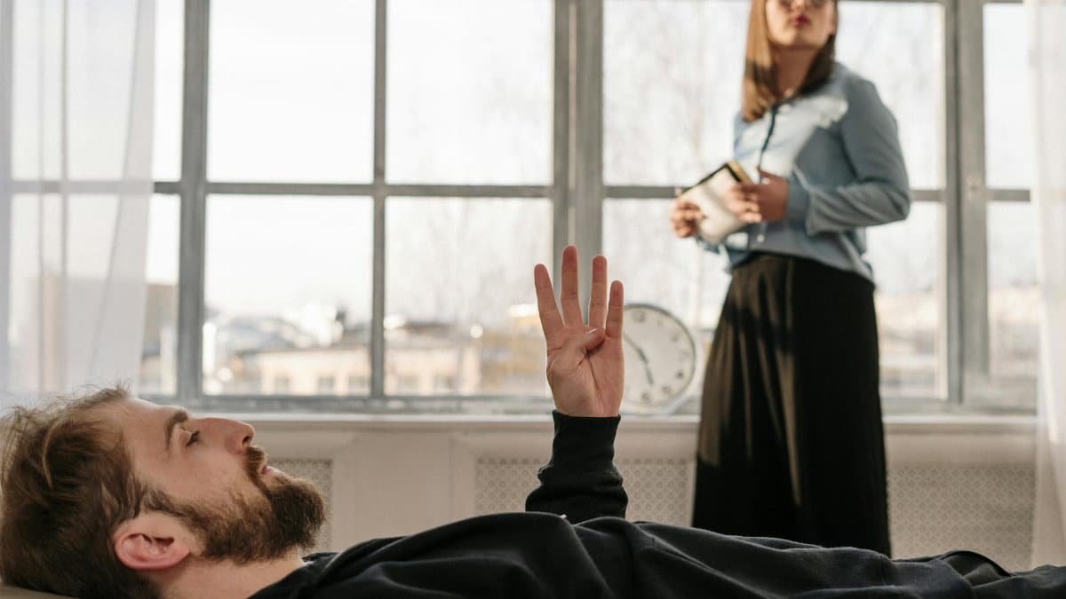 A therapy session with a male patient and a female therapist discussing concerns in a bright office.