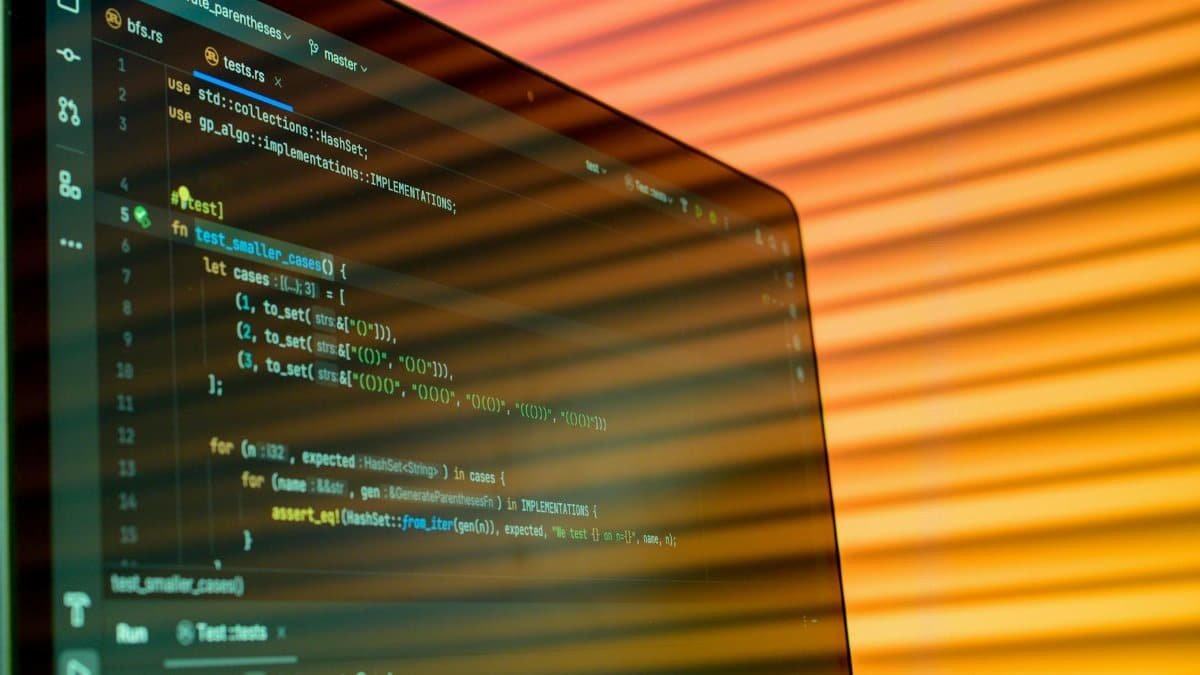 Blurry close-up of a computer screen displaying code with orange lighting.