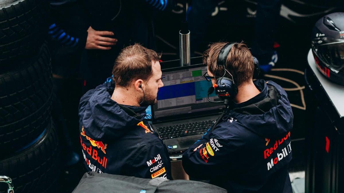 Two Formula 1 team members in discussion over race data at a pit stop.