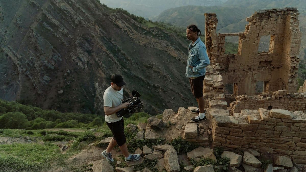 Behind the scenes of a film crew in ancient mountain ruins capturing cinematic shots.