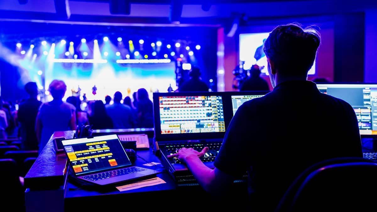 Professional technician managing lighting and sound at a live concert, showcasing modern technical skills.