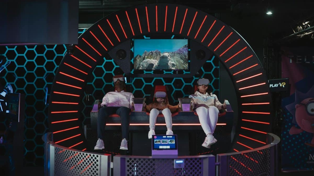 Three people enjoying virtual reality gaming in an indoor arcade setting.