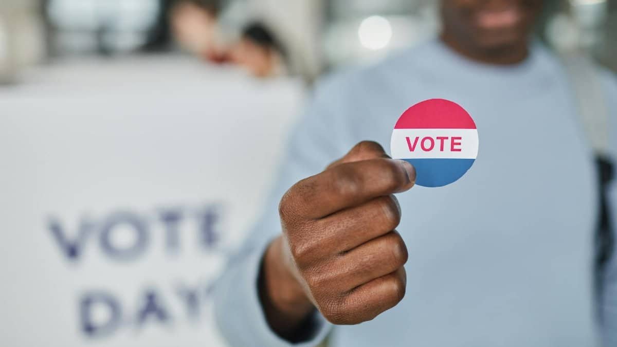 Close-up image of a person holding a vote sticker, symbolizing participation and civic duty.